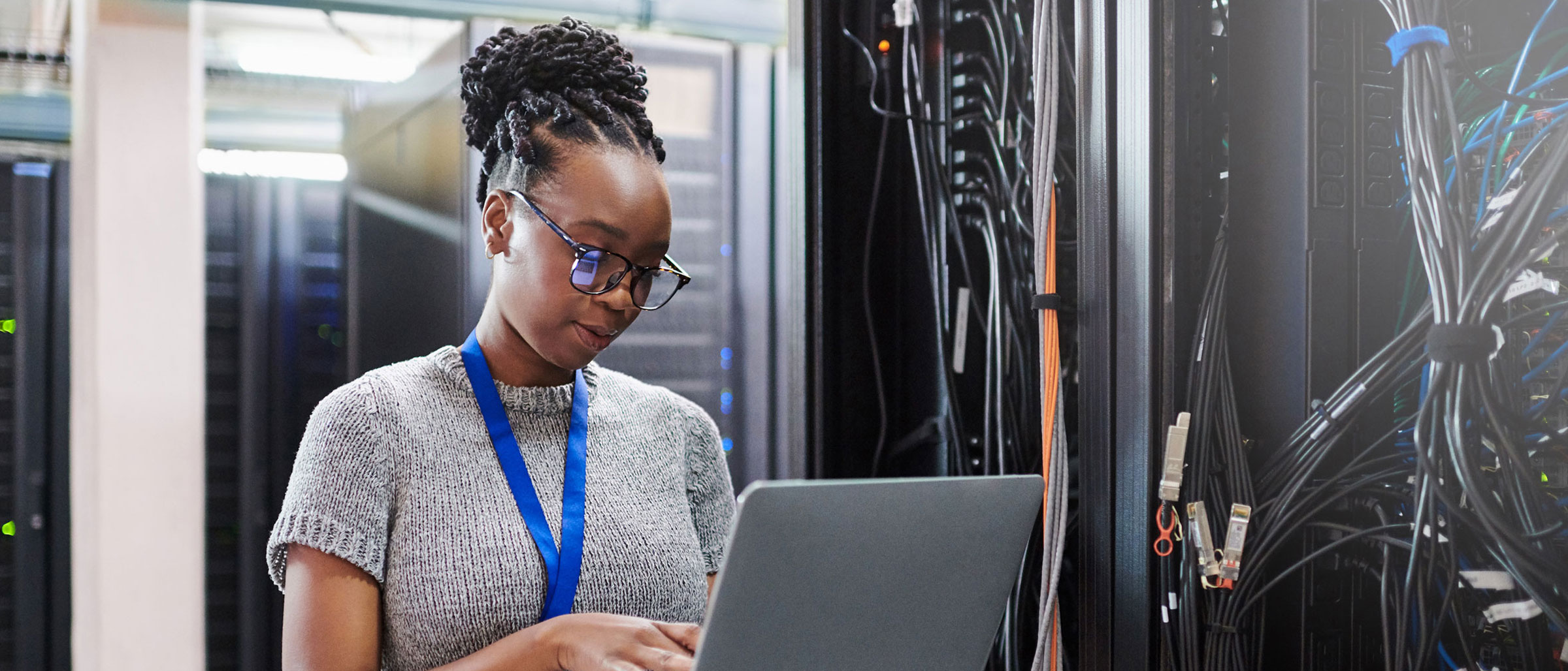 Woman in server room typing on laptop