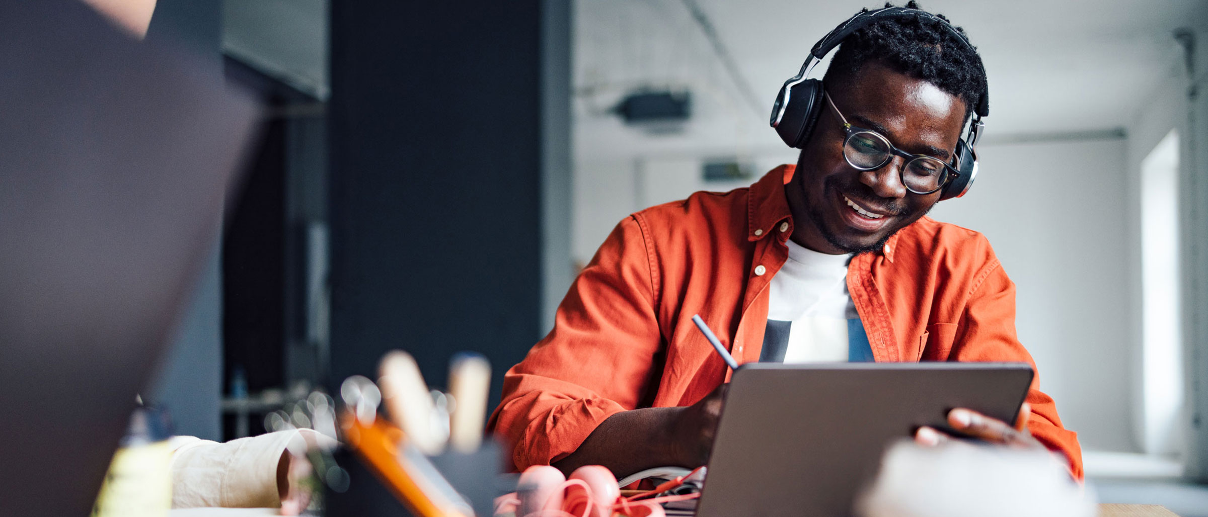 Man wearing headphones writing on tablet