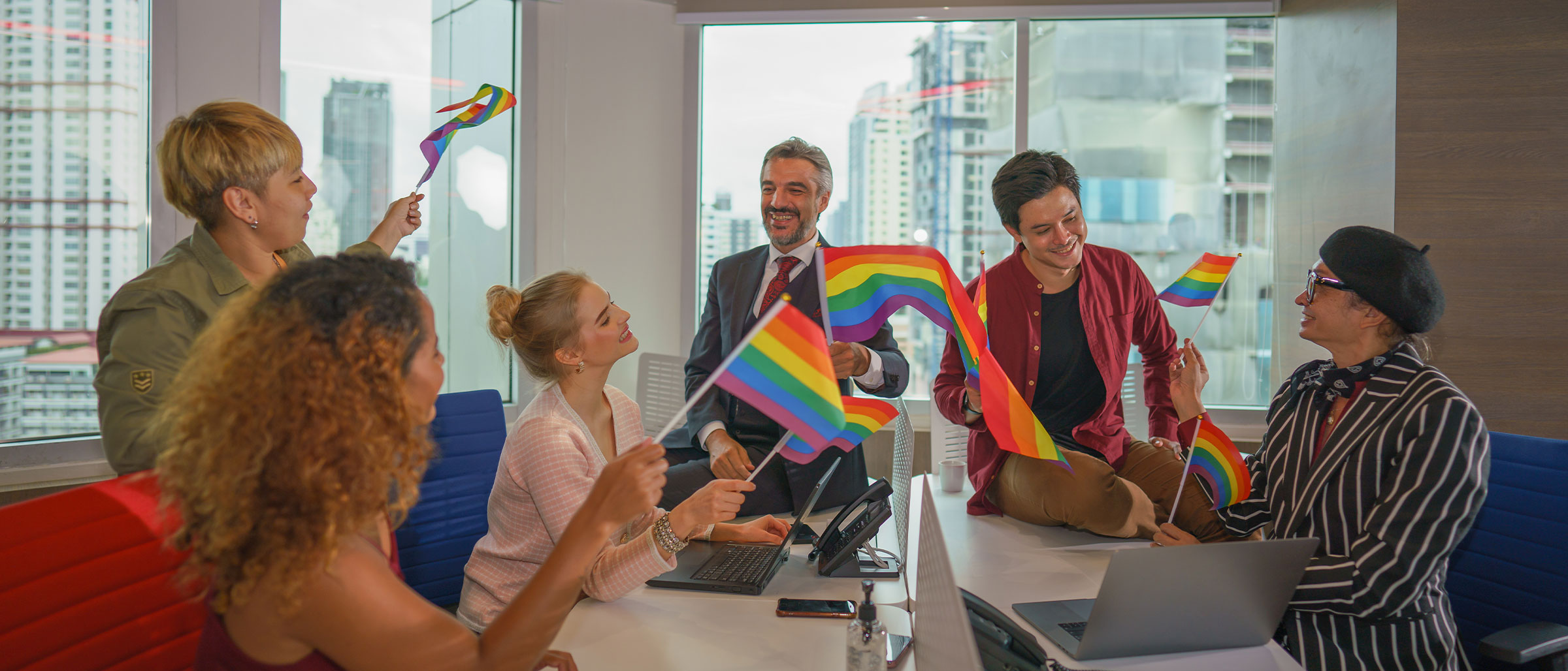 People in boardroom smiling with pride flags
