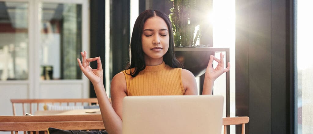 Woman meditating in front of laptop