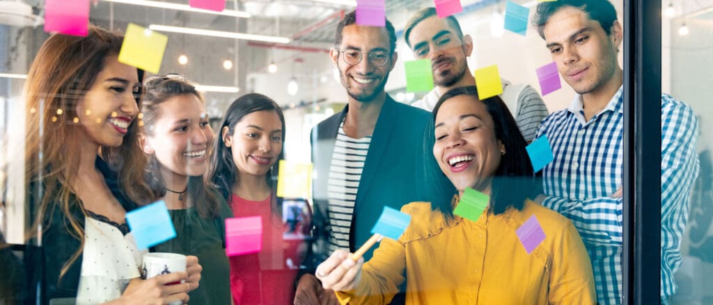 People putting sticky notes on transparent board