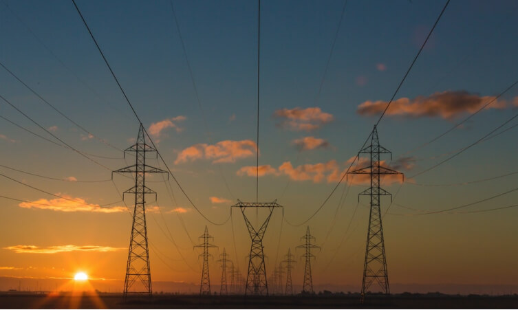 Photo of Power lines in the field with sunset in the background