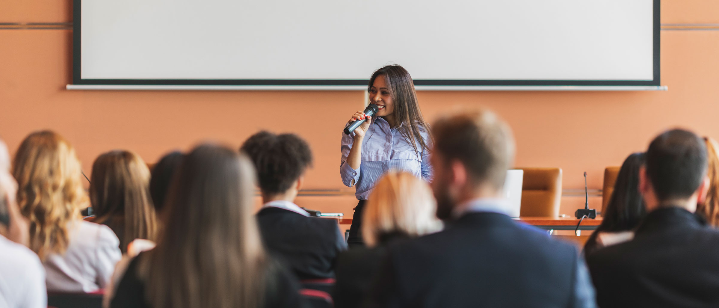 Woman giving speech to audience of professionals