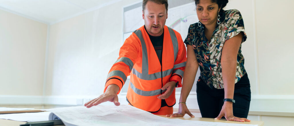 Man in construction vest explaining blueprints