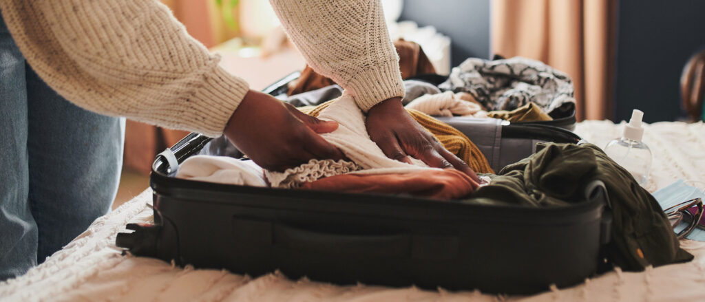 Person packing clothing into suitcase