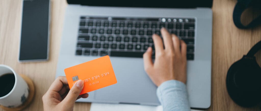 Person Holding Credit Card on laptop