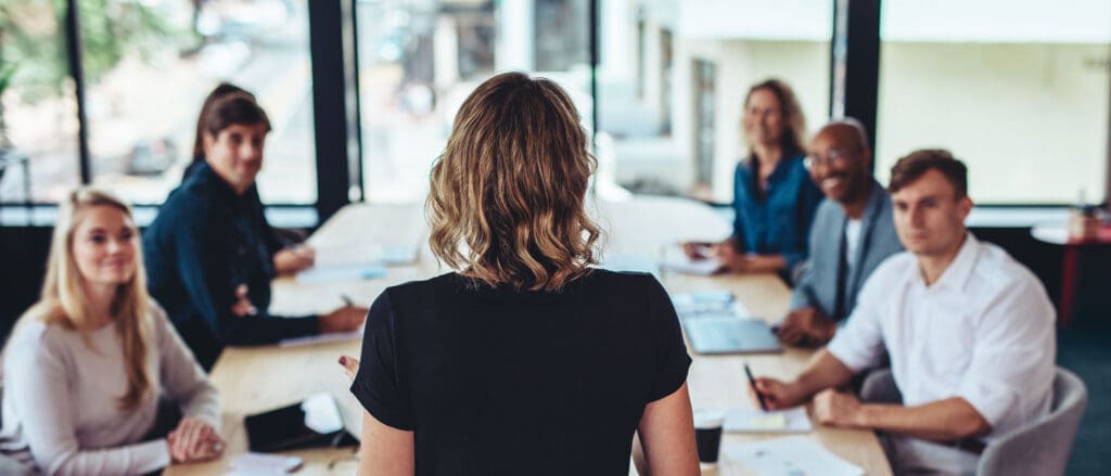 A woman giving a presentation to a group of people at a conference table