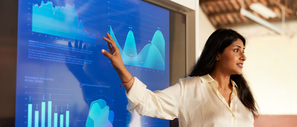 Woman pointing to a screen with graphs