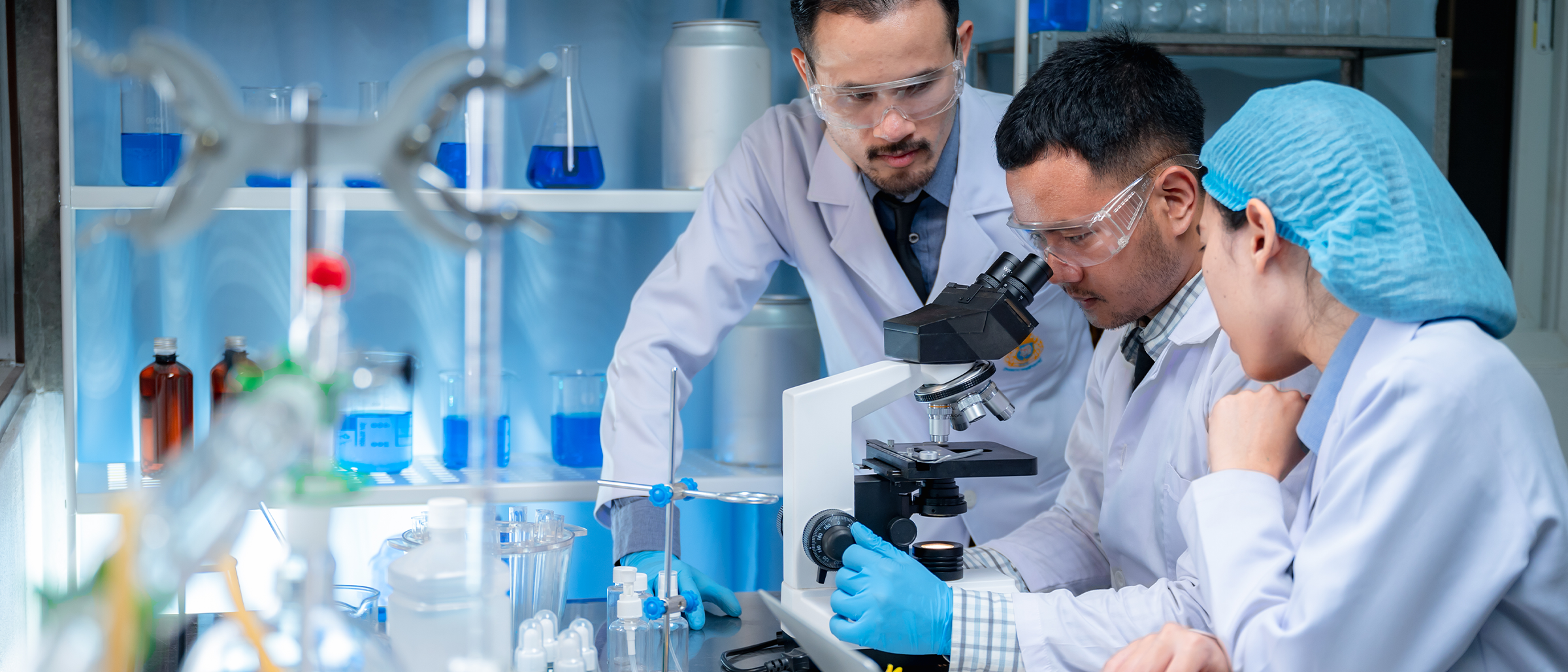 3 Pharmaceutical Professionals looking through a microscope