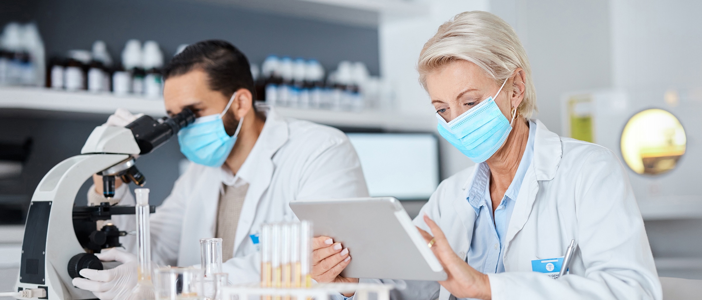 Pharmaceutical professionals looking at tablet and micrsoscope