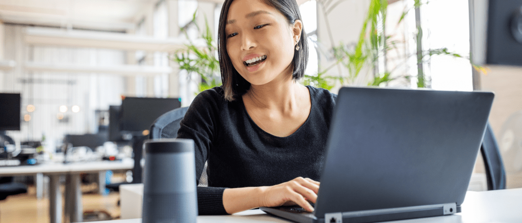 Woman typing on laptop, looking to the side smiling