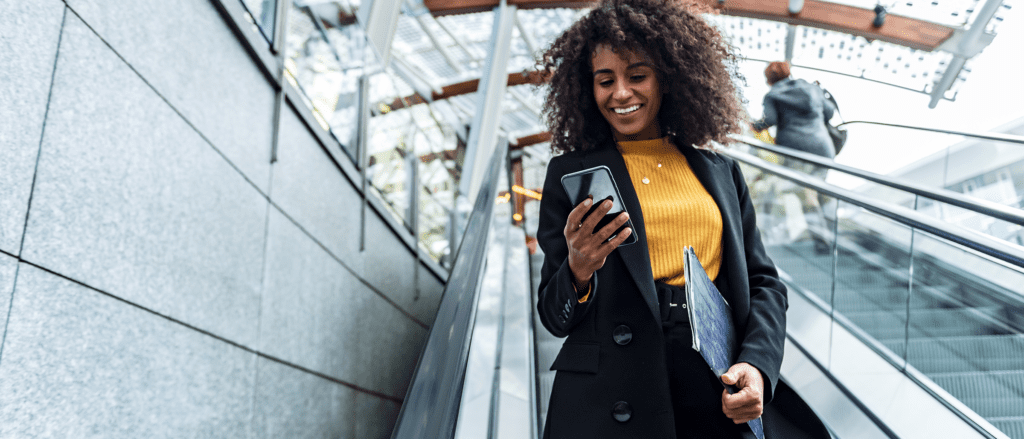 Woman going down escalator looking at phone