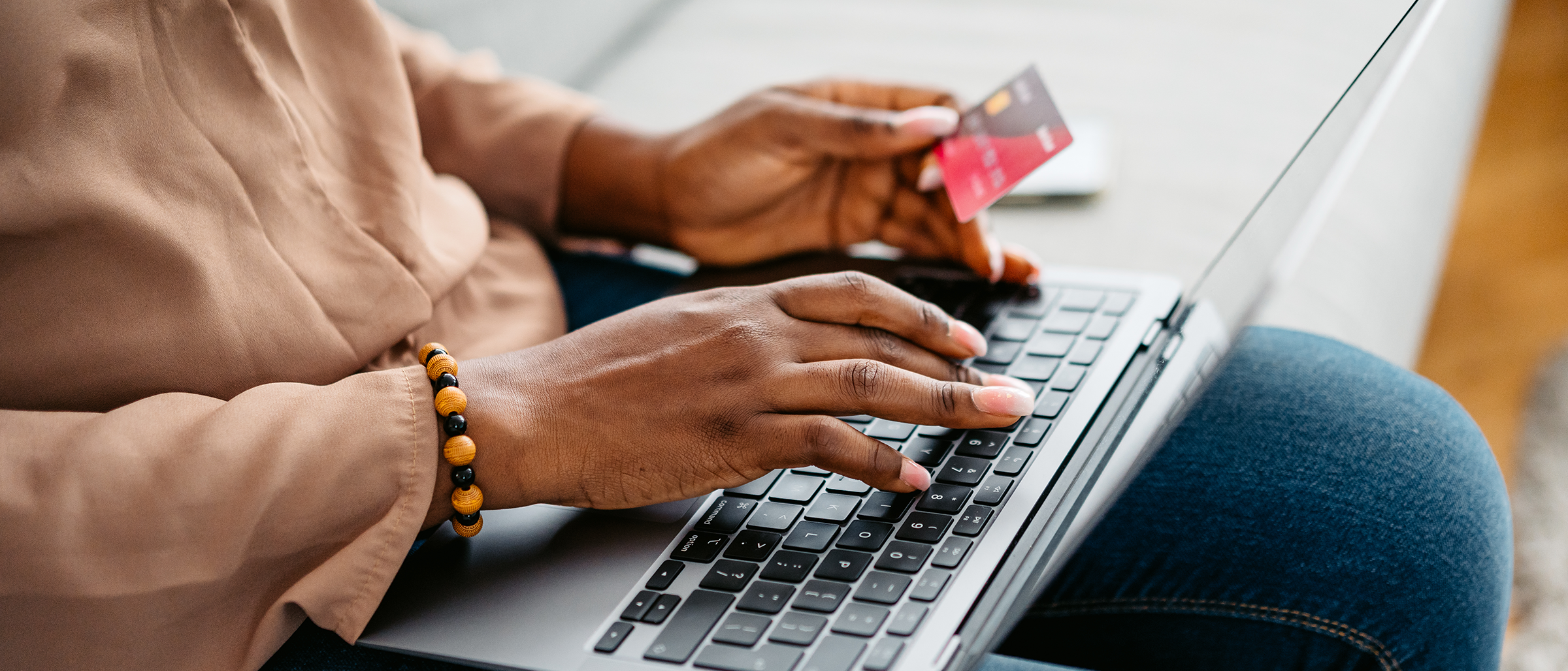 Woman holding bank card over laptop