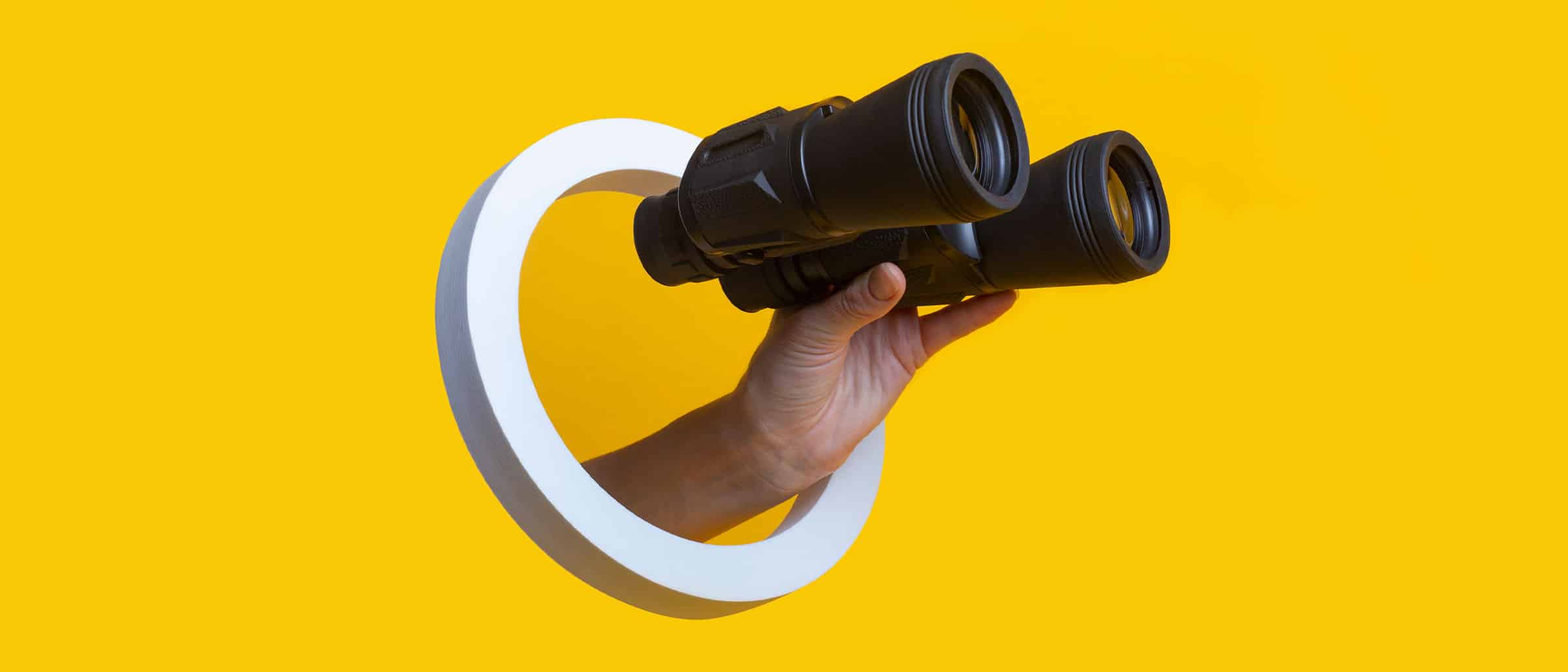 White circle with hand holding binoculars poking through