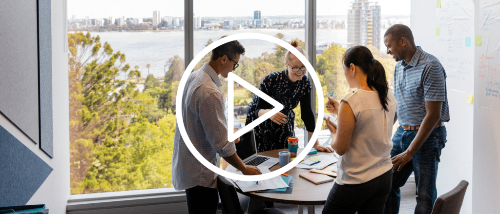 Group of professionals at a conference table with a video play button overlaid