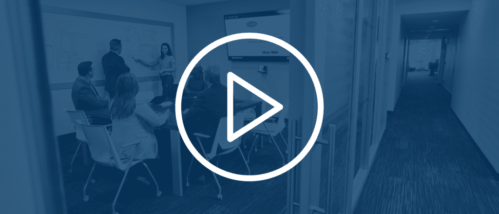 Group of sales professionals in a conference room with a play button over the image