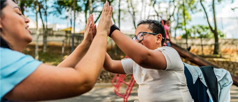 Woman high-fiving a special needs child