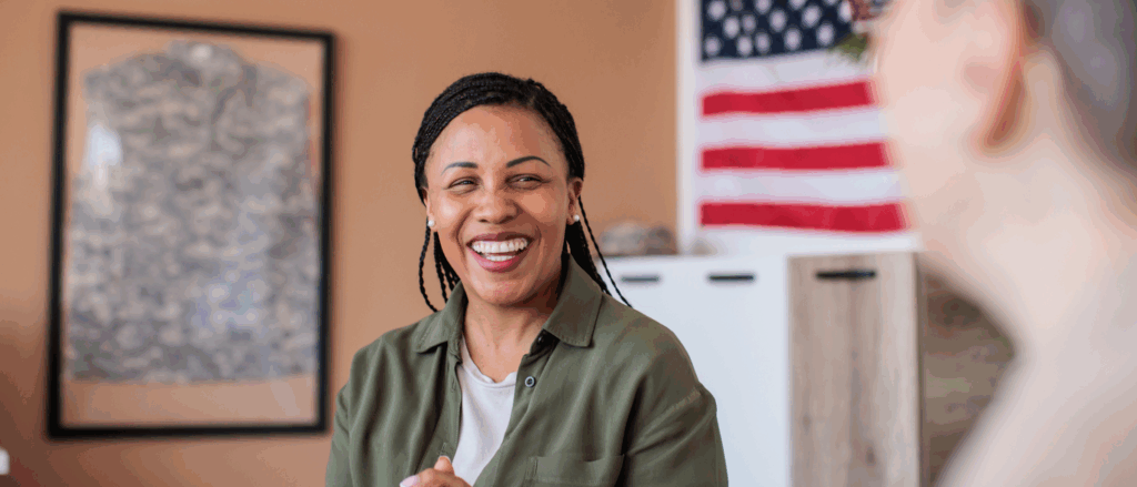 Woman sitting at a desk smiling with American flag in background