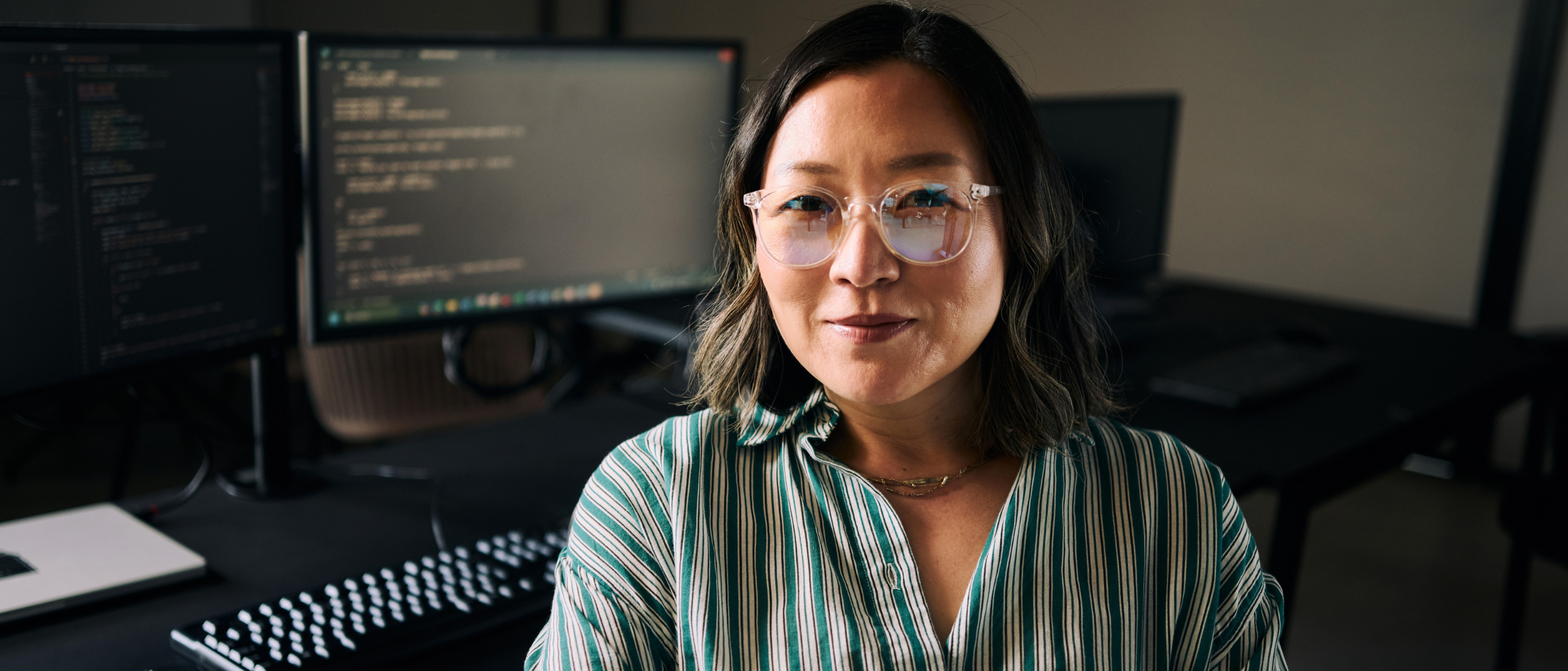 Woman sitting in front of computer screen with code visible