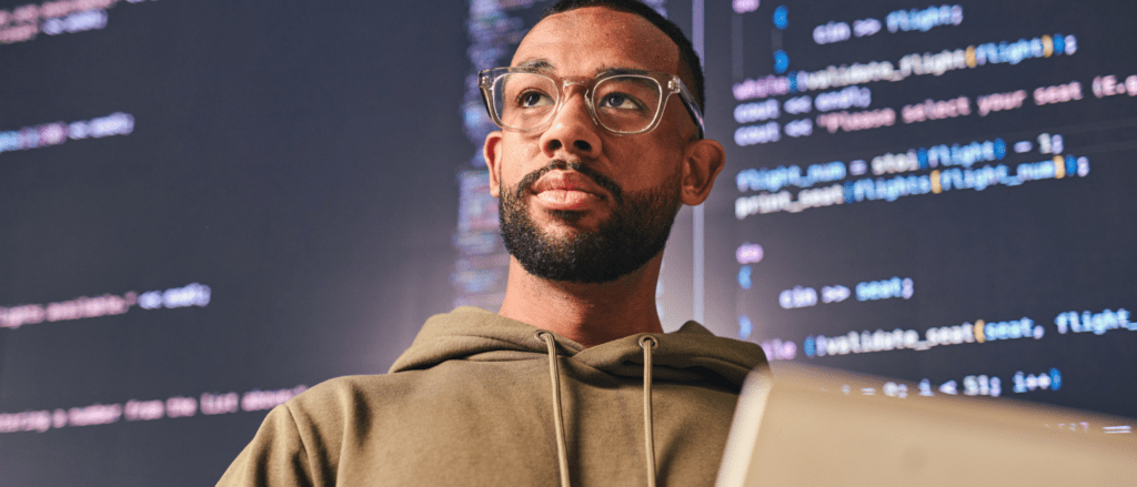Man standing in front of screens with code on them