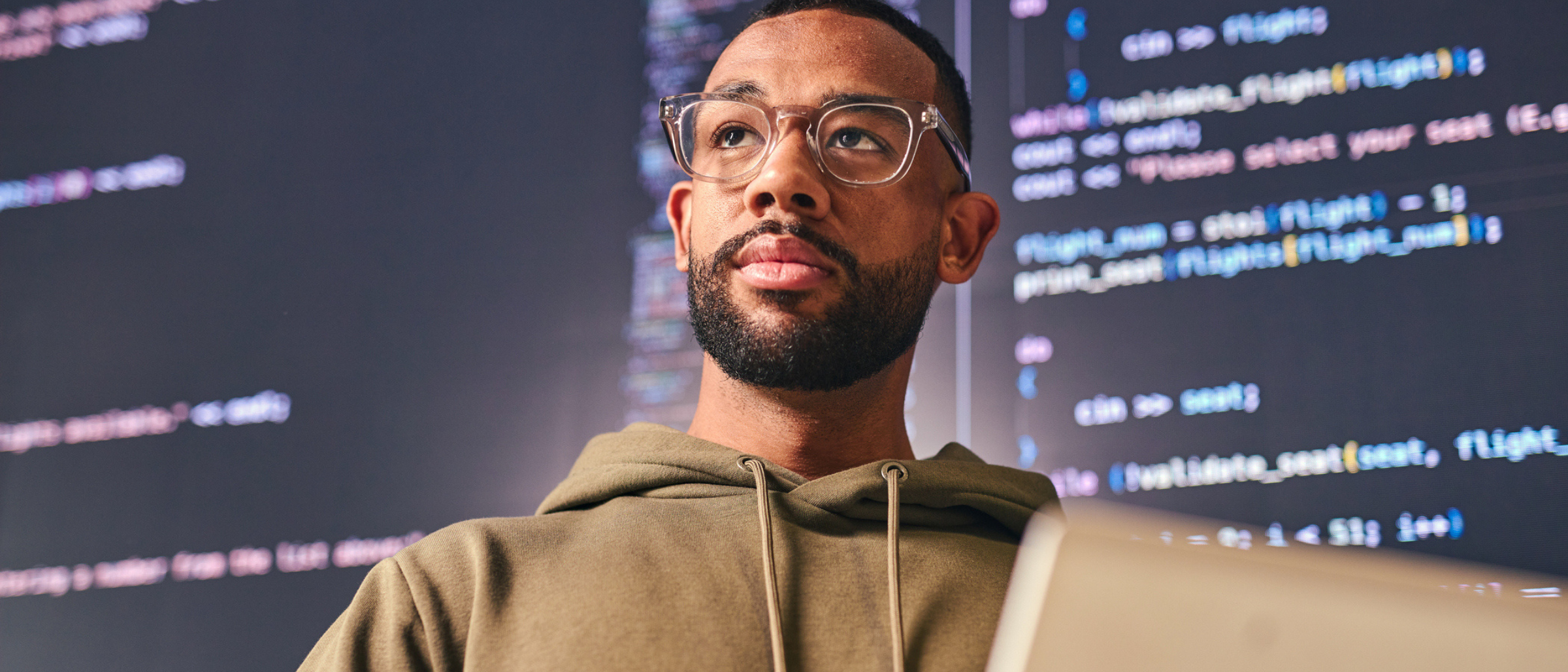 Man standing in front of screens with code on them