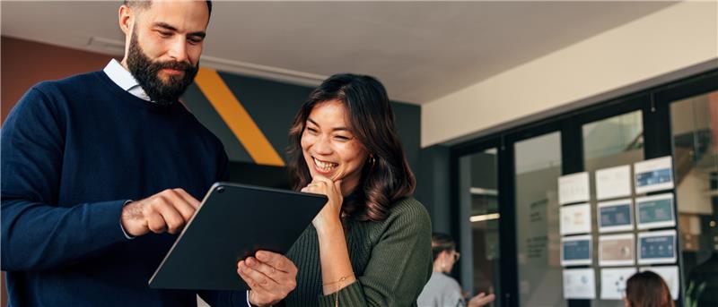 Two professionals looking at a tablet together in an office environment