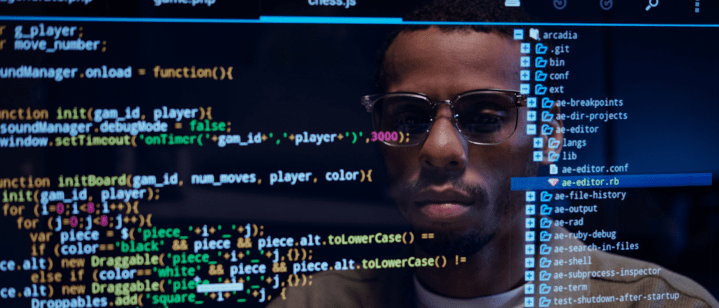 Man's reflection in a computer screen with coding displayed