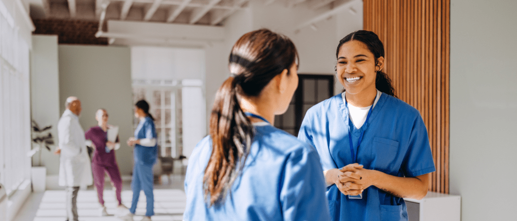 Two nurses talking in a medical facility hallway