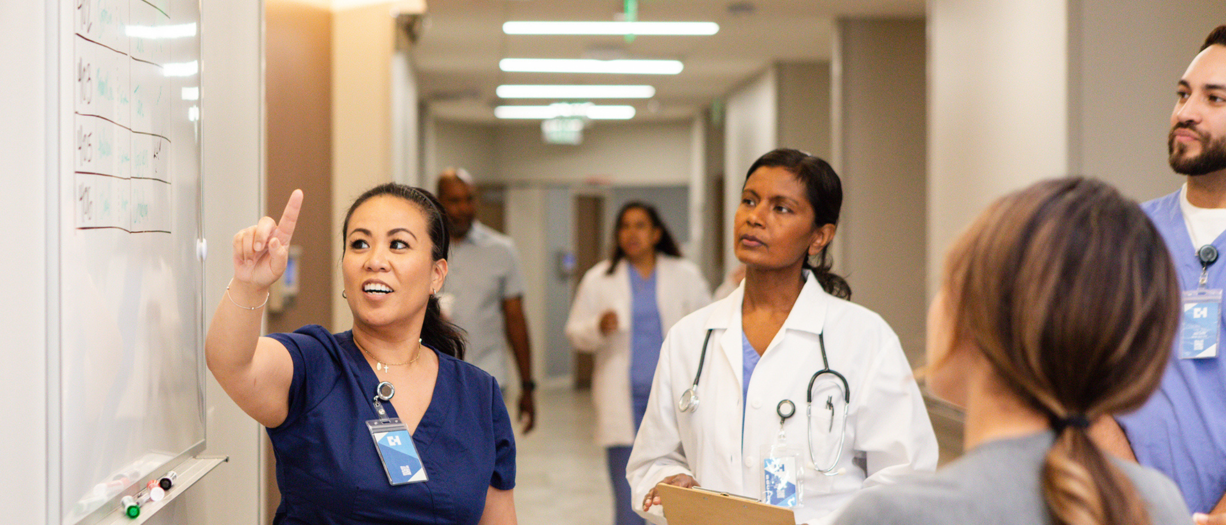 Clinical professionals speaking in a hallway looking at a white board