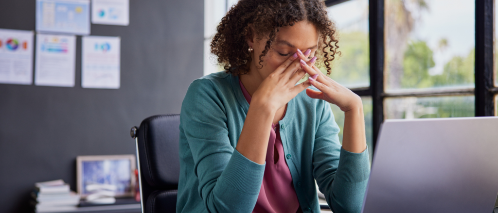 Woman at desk holding her head in her hands