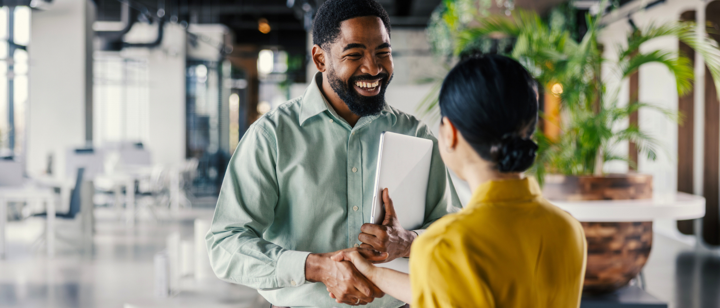 Two professionals in an office space shaking hands