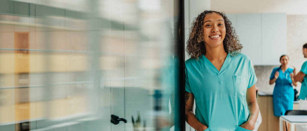 physician in the forefront in a medical building with other medical professionals in the background