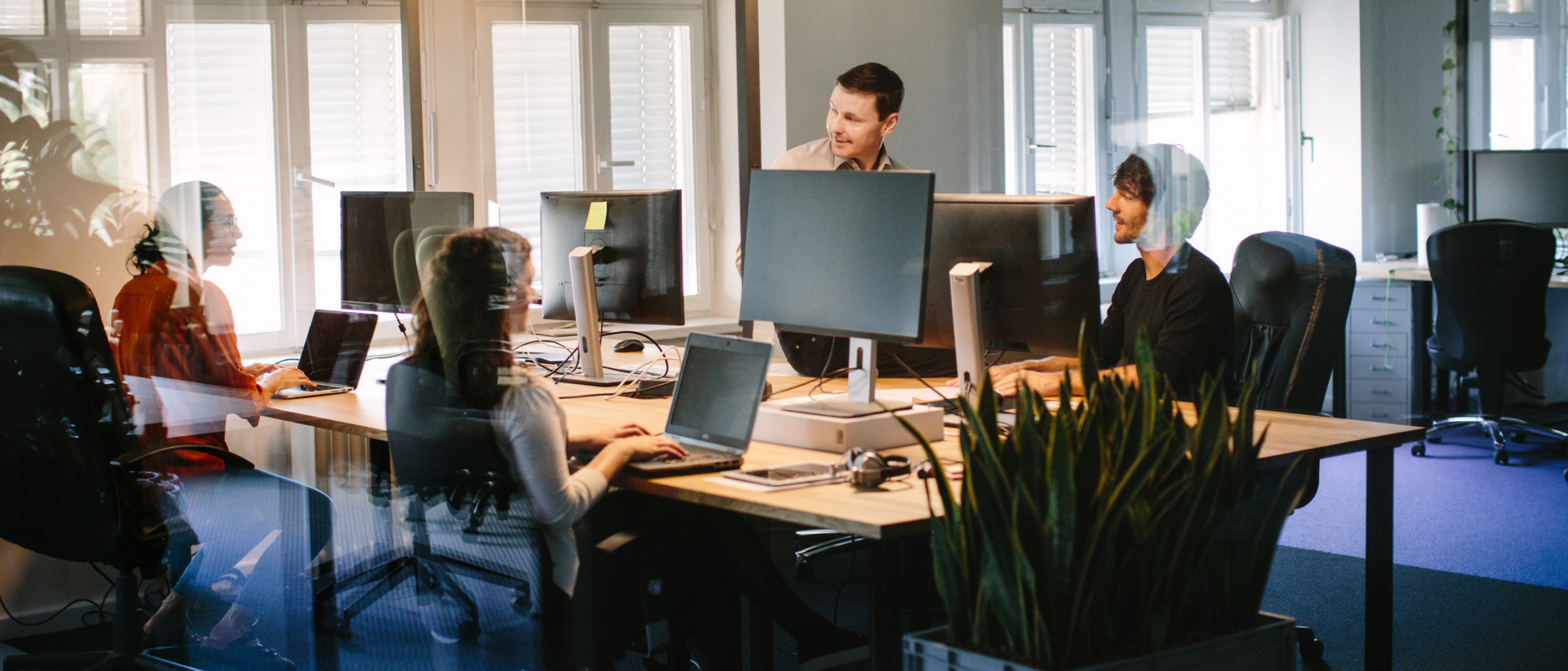 Group of young professionals working at computer stations in an open concept office space