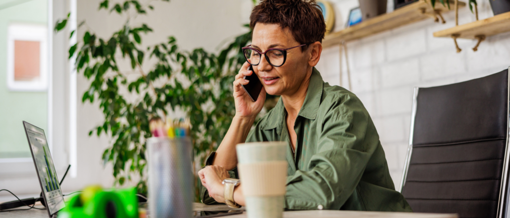 Woman on the phone sitting at a home office desk