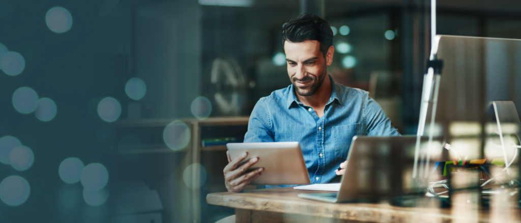 Man sitting in front of a workstation looking at a tablet
