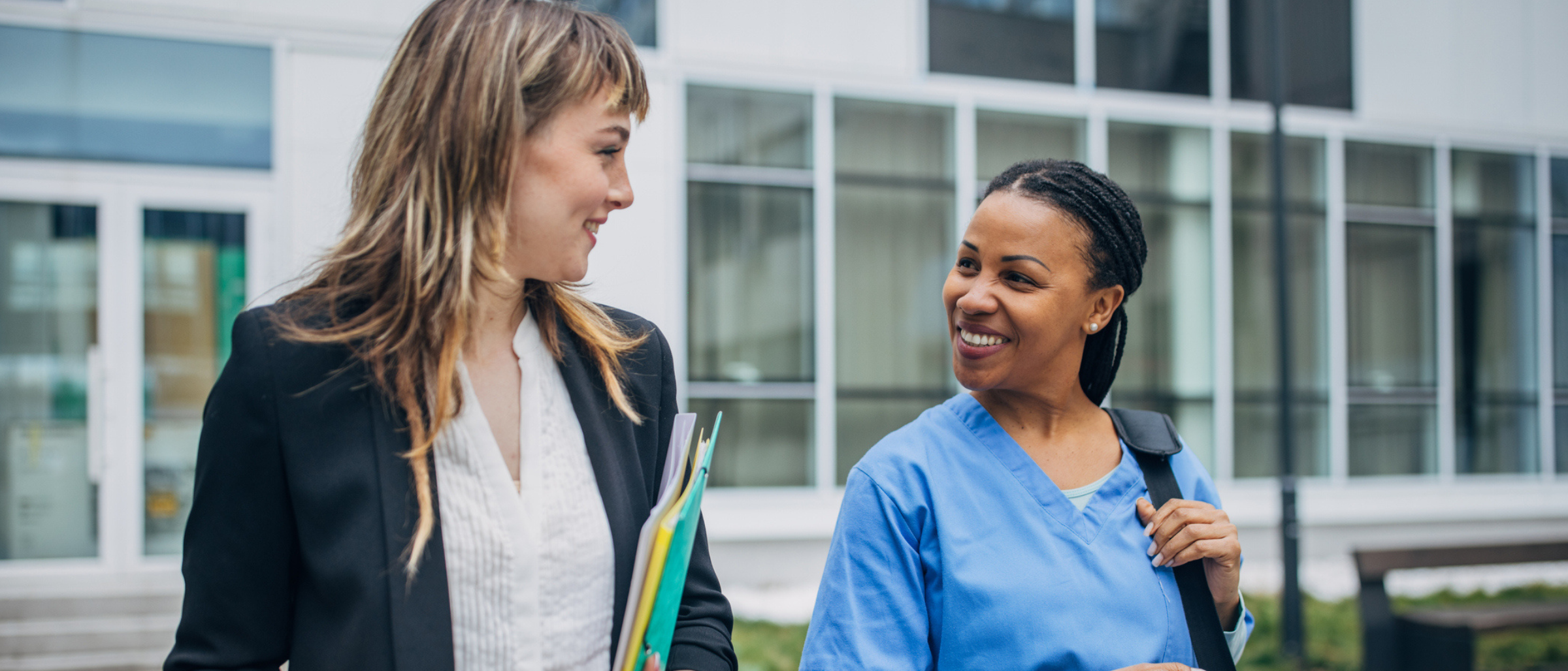 Travel nurse speaking with a colleague outside a medical facility